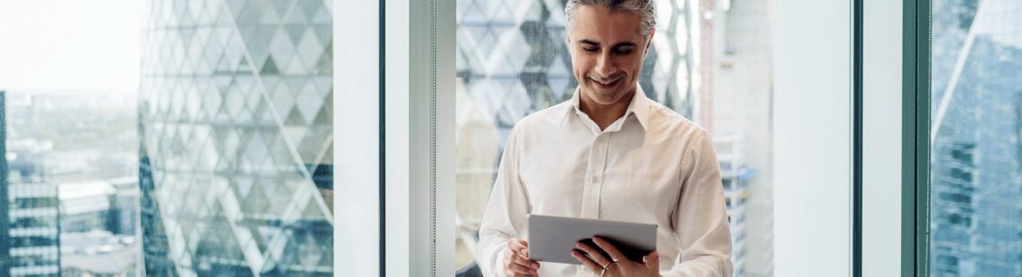 Man in a professional setting looking at his tablet
